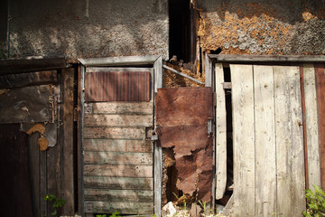 Old weathered wooden shed wall textured background. Rustic damaged wood barn with a closed door at a slum