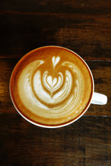 a cup of latte art coffee on wooden background