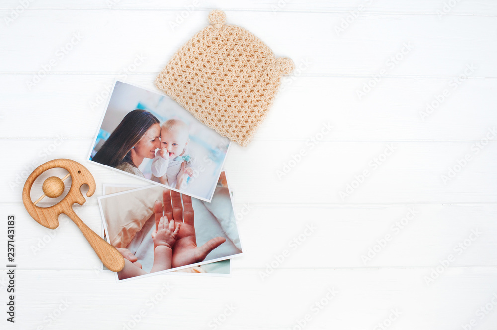 Canvas Prints Baby hat, wooden toy and photos on white wooden background