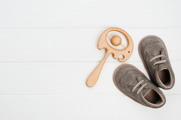 Baby booties and wooden beanbag elephant toy on white wooden background