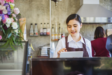 Cheerful young woman cashier is working in cafe