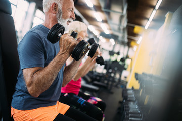 Fit senior sporty couple working out together at gym