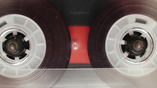 Transparent audio cassette tape playing, macro.