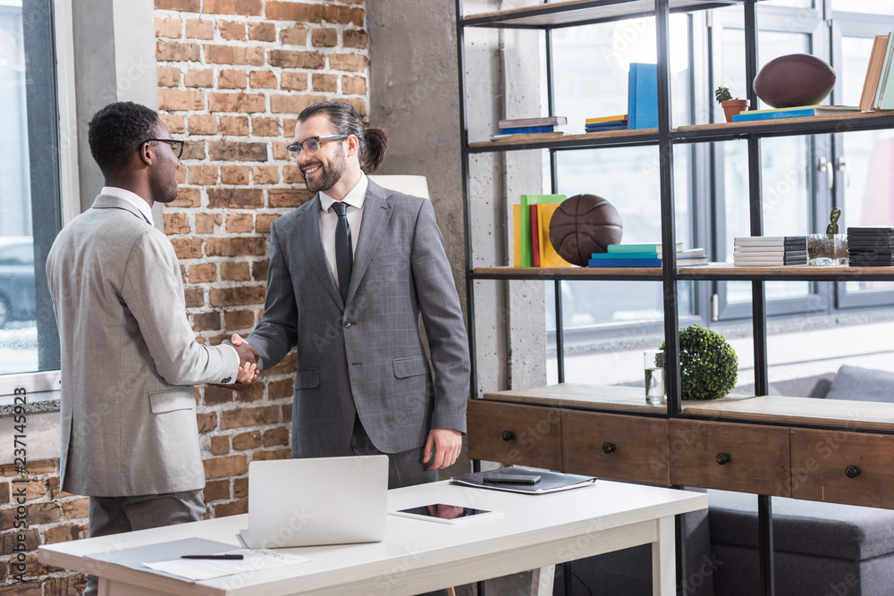 Wall mural multiethnic businessmen shaking hands in modern office