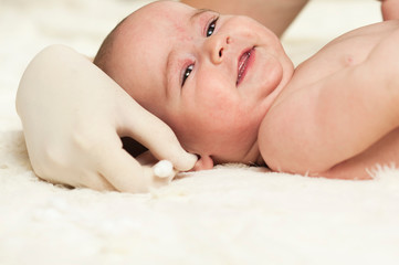 The child at the doctor's office and his ears are cleaned with a cotton swab.