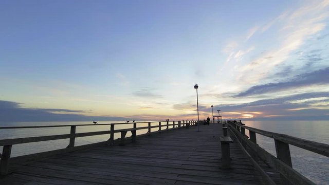 unknown fisherman walking on the pier at sunrise