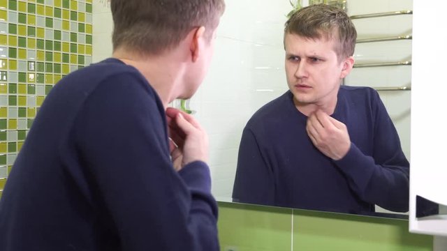 Dandruff on the head. Young man in the toilet room. Very dissatisfied with this situation.