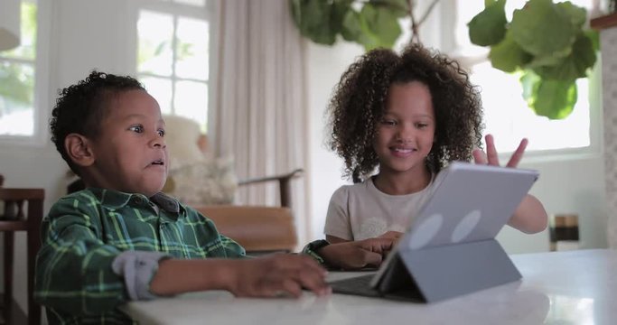 African American brother and sister playing together on digital tablet