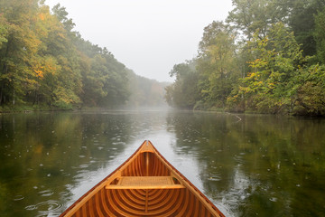 Cedar canoe on a river during a light rain - obrazy, fototapety, plakaty