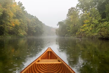Foto op Canvas Cedar canoe on a river during a light rain © Brian Lasenby