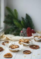 Orange Muffins with Almonds, Sliced Dried Orange / Lemon and Spruce Branch on White Wooden Background