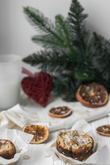 Orange Muffins with Almonds, Sliced Dried Orange / Lemon and Spruce Branch on White Wooden Background