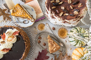 Table with loads of coffee, cakes, cupcakes, desserts, fruits, flowers and croissants. Ancient spoons and a tray, a table in a vintage style.