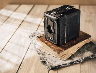 Vintage analogue film camera on a wooden table, old book, clothl. Retro photo. Copy space