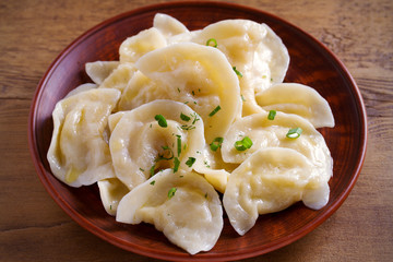 Dumplings, filled with mashed potato in plate on wooden table. Varenyky, vareniki, pierogi, pyrohy - dumplings with filling. Vegetarian dish. horizontal