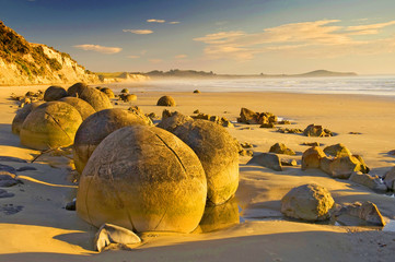 The Moeraki Boulders are unusually large and spherical boulders lying along a stretch of Koekohe Beach on the wave cut Otago coast of New Zealand between Moeraki and Hampden. - obrazy, fototapety, plakaty
