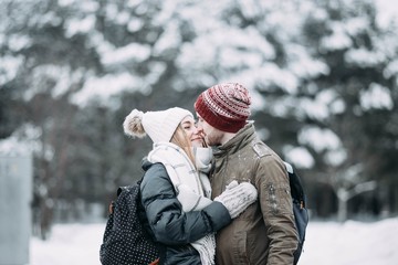 Fototapeta na wymiar young couple in love are walking in the snowy winter forest. Positive beautiful lovers in clothes for the cold time.