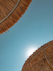 Two Straw Umbrellas and Sun