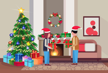 merry christmas happy new year couple give each other present gift box in living room pine tree fireplace home interior decoration winter holiday concept flat horizontal