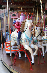 Fototapeta na wymiar Unidentified Little Girl enjoying (Carousel) Merry go round ride at Christmas Market Weihnachtsmarkt in Hannover,Germany