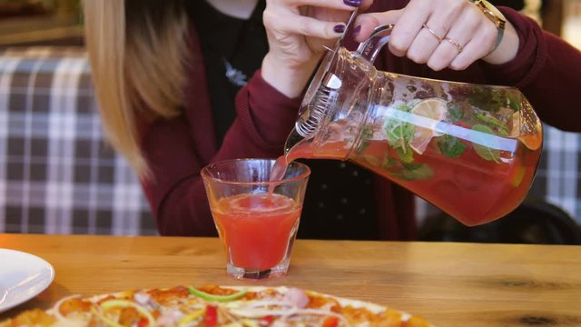 In Cafe At Table Close Up Woman Hands Pour The Juice From Decanter Into A Glass