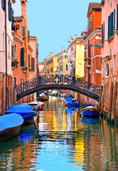 Obraz na płótnie Canvas Venice colorful corners with iron bridge, old buildings and architecture, boats and beautiful water reflections on narrow canal, Italy