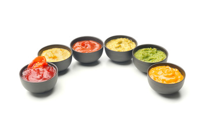 Different tasty sauces in bowls on white background