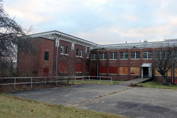 Fototapeta na wymiar Boarded up and abandoned brick mental hospital asylum building 