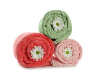Obraz na płótnie Canvas Rolled clean soft towels with flowers on white background
