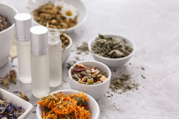 Aromatic dried flowers with herbs and essential oil on grey table