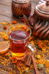 Glass cup of hot tea and dried flowers on wooden table