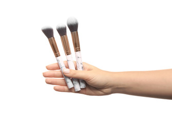 Woman holding makeup brushes on white background