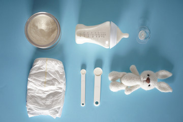 Composition with feeding bottle of baby formula and powder on color background