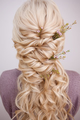Back view of an elegant trendy hairstyle, interlacing curls and decorating with flower petals