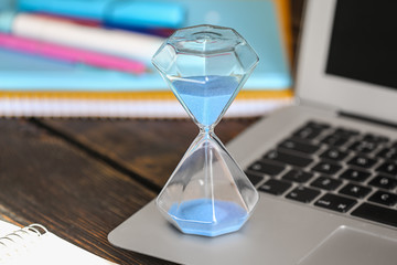 Hourglass on laptop keyboard. Time management concept