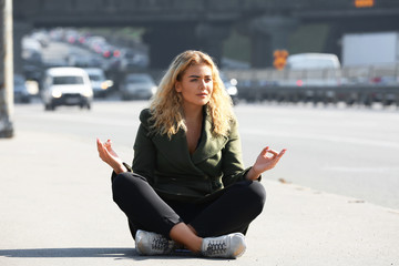 Fototapeta premium Beautiful young woman meditating on city street