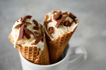 Waffle cones with delicious ice cream in cup on grey table