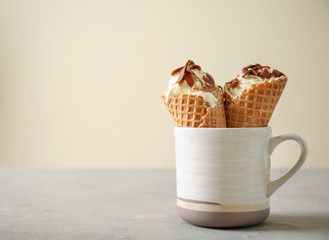 Waffle cones with delicious ice cream in cup on grey table