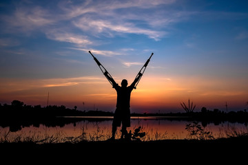 Disabled man with crutches in sunrise background.