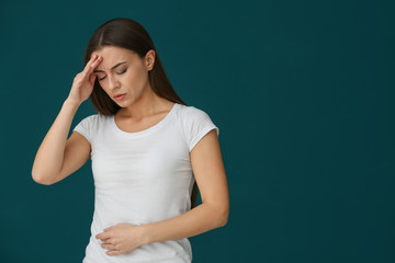 Woman suffering from headache on color background