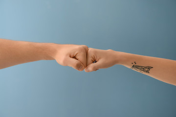 Man and woman bumping fists on color background