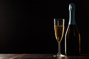 bottle of champagne and glasses over dark background