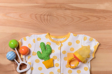 Baby clothes and toys on wooden background, top view