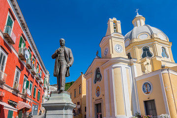 Antonio Scialoja statue on Terra Murata quarter and Santa Maria delle Grazie church, Marina di Corricella, Procida, Gulf of Naples, Campania, Italy. - obrazy, fototapety, plakaty