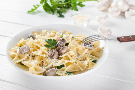 Close up pasta with mushroom and parsley on white wooden table.