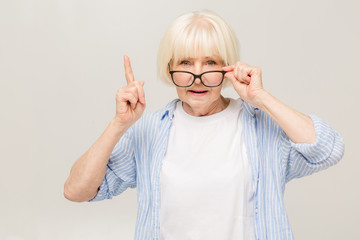 Portrait of mature business woman smile while standing against white background. Photo of old woman wearing glasses. A beautiful modern grandmother is a pensioner.