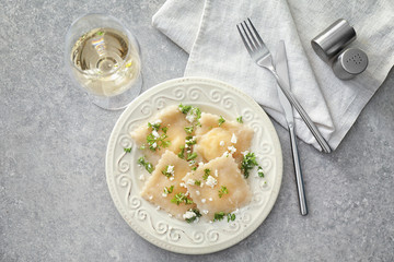 Plate with tasty ravioli on table, top view