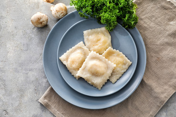 Plate with tasty ravioli on table, top view