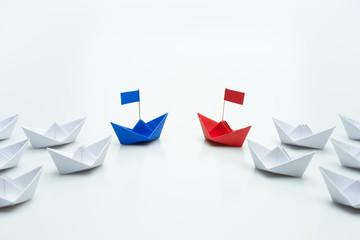 Blue and red paper ship leading among white. leaders of two business teams or competition of two...