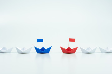 Blue and red paper ship leading among white. leaders of two business teams or competition of two...